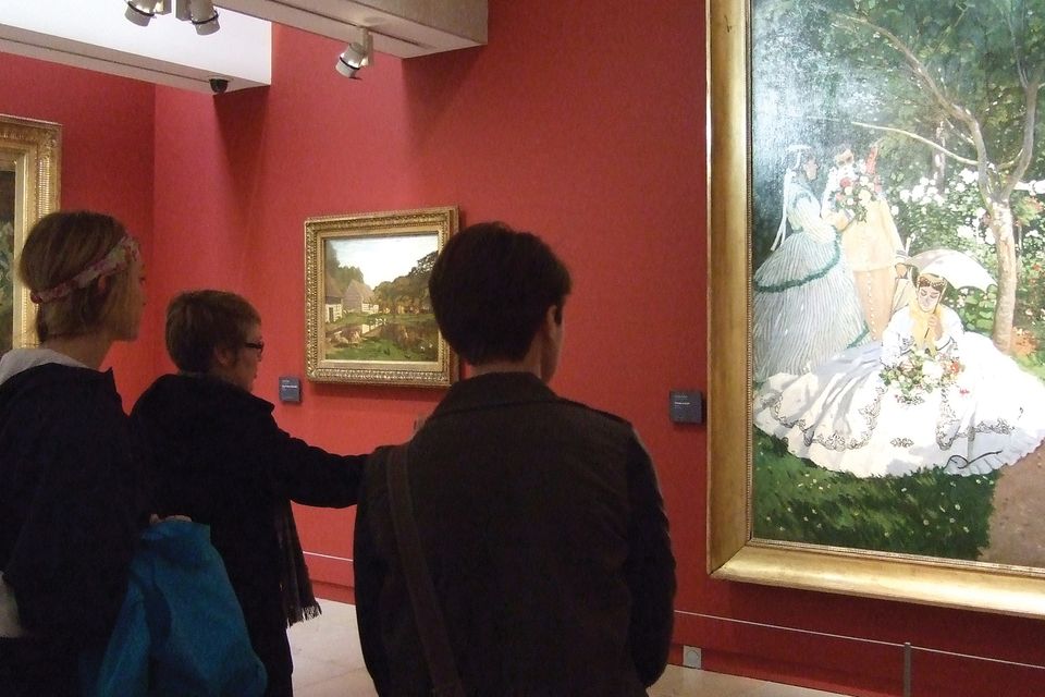 Three people viewing a painting in a museum