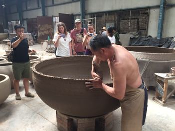 Students watching ceramicist create a large pot