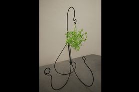 metal holder with green sculpted plant