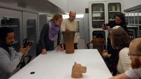 people viewing ancient ceramics on table in vault